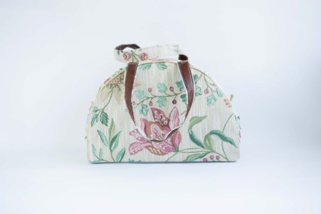 Dekoratiivse lillemusriga pastellsetes toonides kangast reisikott.