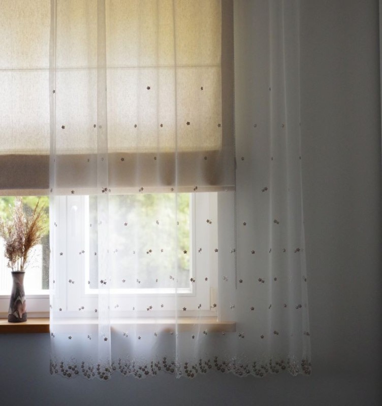 Õrn ja õhuline beeži-valge tooni lillemotiivi tikandiga lühem tüllkardin.