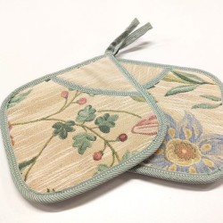 Heledal põhjal pastellsetes toonides taimemustriga taskuga pajalapid.